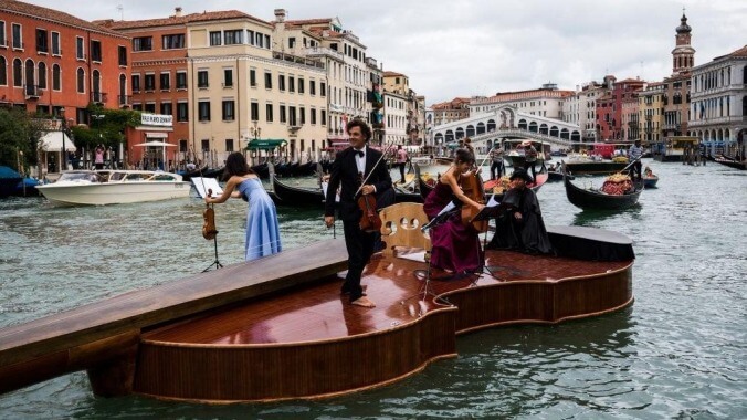 Normal-sized string quartet perform atop very big floating violin boat in Venice