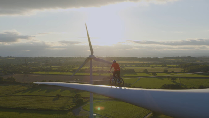 Cyclist rides along a wind turbine blade for our amusement and climate change fundraising