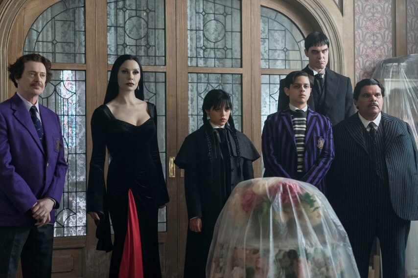 (L to R) Steve Buscemi as Barry Dort, Catherine Zeta-Jones as Morticia Addams, Jenna Ortega as Wednesday Addams, Isaac Ordonez as Pugsley Addams, Joonas Suotamo as Lurch, Luis Guzmán as Gomez Addams in episode 201 of Wednesday. Cr. Jonathan Hession/Netflix