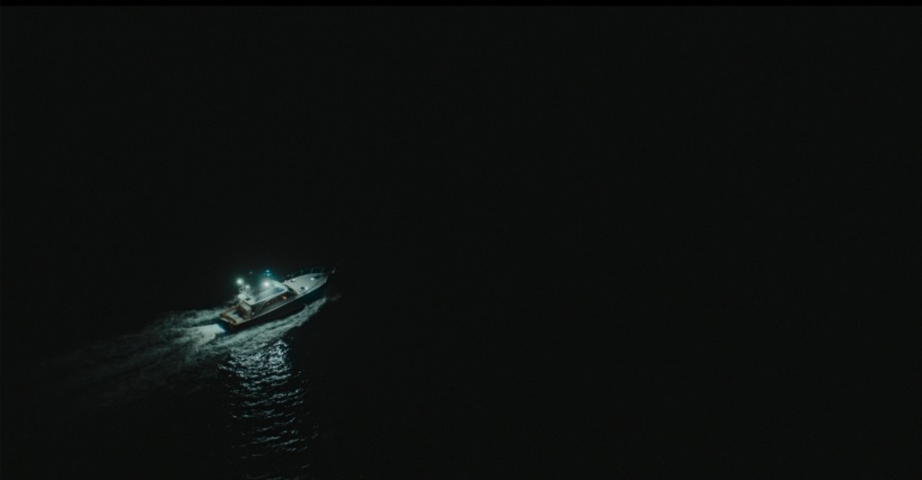 Overhead image of a boat driving at night, in completely dark and terrifying waters
