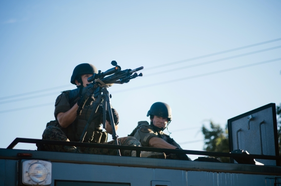 Police train a sniper rifle on protesters while sitting atop a SWAT vehicle in Ferguson, Missouri in 2014