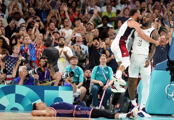 PARIS, FRANCE - AUGUST 08: Stephen Curry of United States and LeBron James of United States celebrate, Aleksa Avramovic of Serbia disappointed on the floor after the Men's Basketball Semifinal Game between USA and Serbia on day thirteen of the Olympic Games Paris 2024 at Bercy Arena on August 08, 2024 in Paris, France.