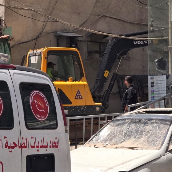 A worker uses heavy machinery to shift through the rubble, looking for victims