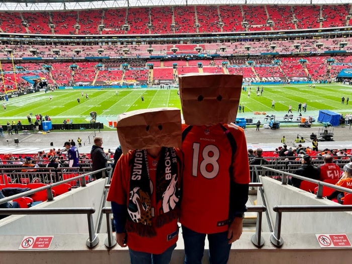 Two friends wearing Broncos jerseys and bags over their heads at their game at Wembley Stadium in London