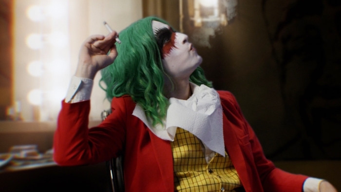 The Joker sitting down and smoking a cigarette 