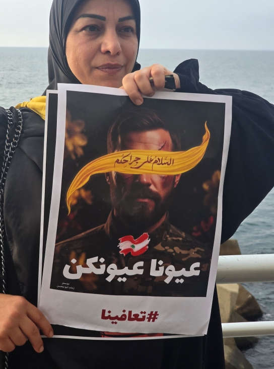 A woman holding up a protest sign with the Lebanese flag on it