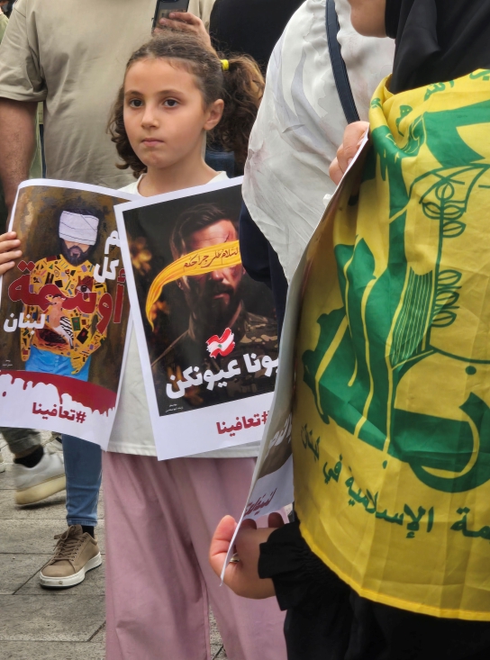A small girl holds up two signs at a protest