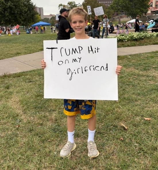 Middle school-ish aged kid holding up a "Trump hit on my girlfriend" sign